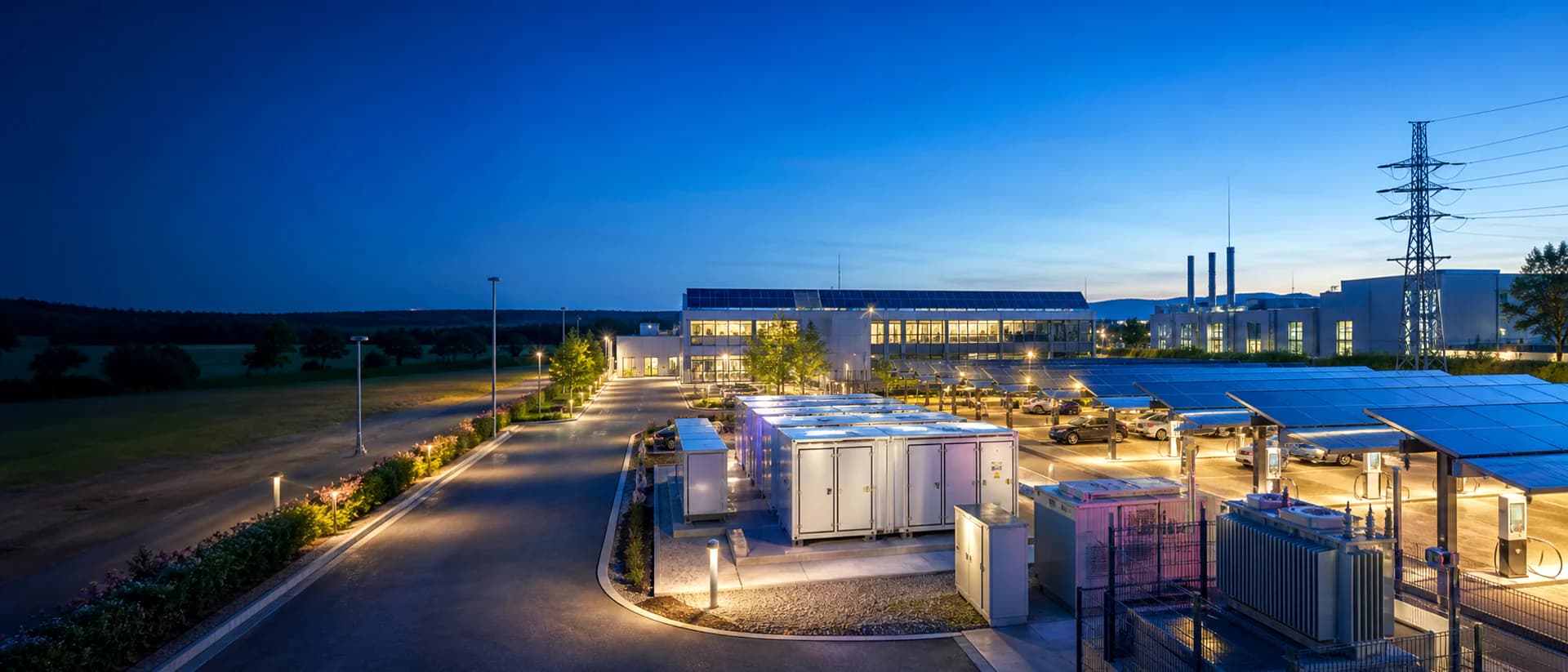 Blue-Hour-Gewerbestandort mit PV-Dach, Batteriespeichern und Netztechnik als illustrative EVU-Standortstruktur.